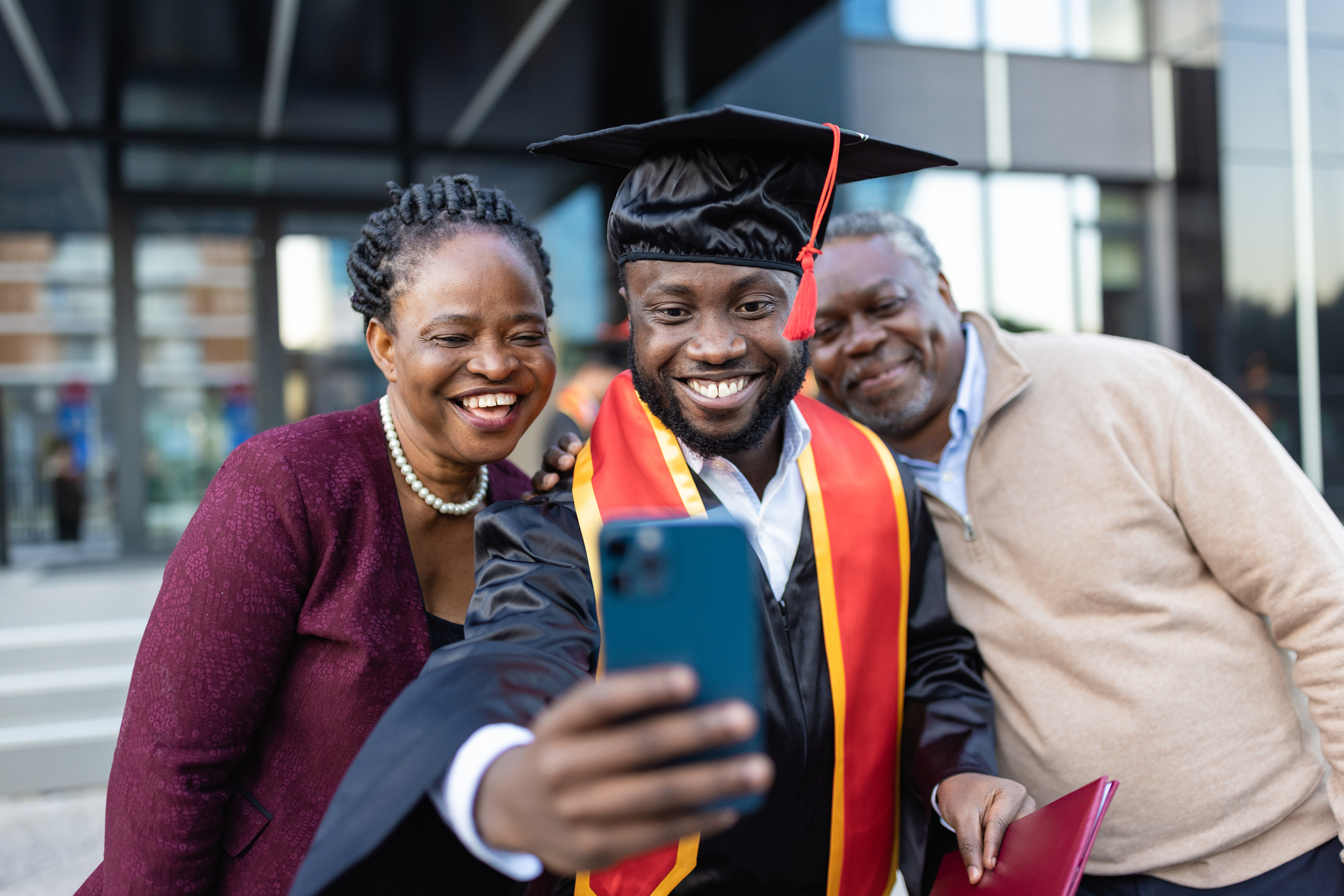 Excited African American college graduate with his family after the graduation ceremony