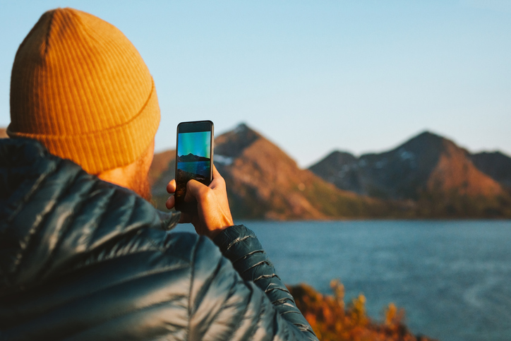 Man with smartphone taking photo in Norway travel lifestyle adventure vacations outdoor blogger influencer lifestyle modern online technology